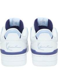 White sneakers with blue accents, featuring a smooth leather upper, textured heel, and signature detail on the back.