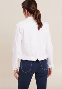Witte denim jas met lange mouwen, knopenmanchetten en een cropped ontwerp. Heeft zichtbare stiksels en een split aan de achterzoom.