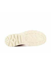 Semelle de chaussure avec une surface en caoutchouc texturé, de couleur beige, présentant de profonds sillons et des motifs circulaires pour une meilleure adhérence.