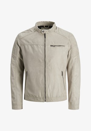 Light beige jacket made of soft, textured fabric. Features a zip front, stand collar, quilted shoulder accents, and zippered pockets.