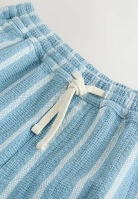 Shorts bleu clair texturés avec des rayures blanches verticales et une taille élastique dotée d'un cordon blanc noué.