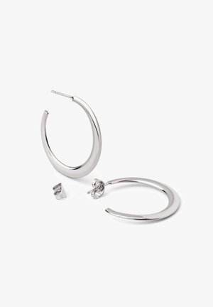 Srebrne kolczyki-koła o gładkim, zakrzywionym wzorze. Posiadają zapięcie na sztyft oraz mały dodatkowy kolczyk w kształcie koła.