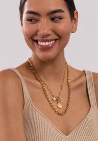 Goldfarbene, mehrlagige Halsketten mit einer massiven Kette, einer zarten Gliederkette und einem Anhänger mit einer Perlenakzent und einer runden Medaille.