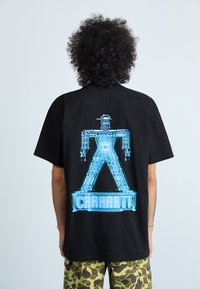 Camiseta de algodón negra con un diseño digital en azul de un circuito que representa una figura humana y el texto "Carhartt" impreso en la parte posterior.