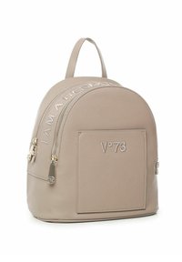 Zaino in pelle beige con forma arrotondata, manico superiore, dettagli con logo, una tasca frontale e chiusure con zip. Presenta accenti in hardware color oro.