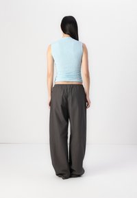 Lichtblauw, gestructureerd mouwloos topje gecombineerd met loszittende, donkergrijze broek. De outfit heeft een ontspannen ontwerp en een elastische taille.