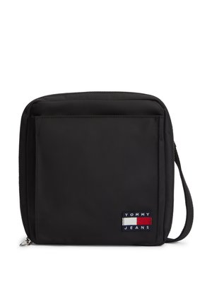 Schwarze quadratische Crossbody-Tasche mit Frontfach, Reißverschluss, Handgelenkschlaufe und Tommy Jeans Logo-Patch in Rot, Weiß und Marineblau.