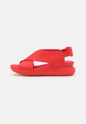Red leather sandal with a wide cross strap and open toe. The design features a molded foam sole and a rear ankle strap for support.
