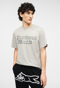 Γκρι βαμβακερό t-shirt με το γραφικό "Icecream World" σε μαύρη γοτθική γραμματοσειρά, συνδυασμένο με μαύρη φόρμα με γραφικό ενός λευκού σκύλου.