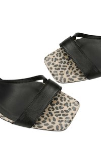 Stel zwarte sandalen met brede bandjes en een vierkante teen met luipaardprint op een witte achtergrond.