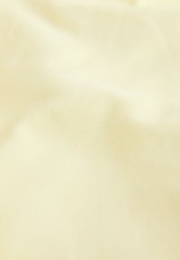 Tissu de couleur crème avec une texture subtile en nid d’abeille et des plis doux créant des ombres délicates.