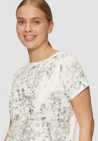 Korte mouwen top in het wit met een gestructureerd, abstract zilverkleurig patroon. Ronde halslijn en lichtgewicht stof zorgen voor een casual, luchtige uitstraling.