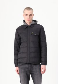 Chaqueta aislante negra con capucha gris, parte delantera abotonada y patrón acolchado. Presenta un bolsillo en el pecho con cierre a presión y un acento de marca.