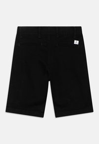 Shorts noirs longueur genou avec passants de ceinture, deux poches passepoilées à l’arrière, et une petite étiquette blanche de la marque sur la poche droite.