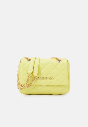 Prošívaná žlutá kabelka se zlatým řetízkovým popruhem a logem. Má strukturovaný tvar a hladkou texturu. Kompaktní velikost na nezbytnosti.