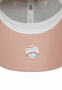 Gorra de béisbol rosa con visera blanca y forro de malla. Presenta una pegatina temática de béisbol en la parte inferior de la visera.