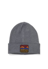 Gorro de punto gris con un puño doblado y un parche bordado colorido que presenta montañas y el logo de Timberland. Textura suave.