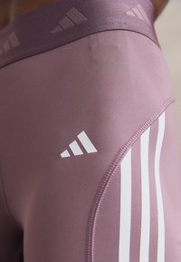 Högmidjade, rosa träningsleggings med vita sidsränder och en strukturerad midjeresår med en subtil logotyp. Mjukt, stretchigt tyg.