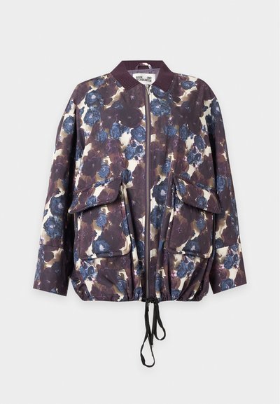 Veste bomber à motif floral avec des fleurs bleues et violettes, fermeture éclair à l'avant, deux grandes poches à rabat, col côtelé et ourlet avec cordon de serrage.