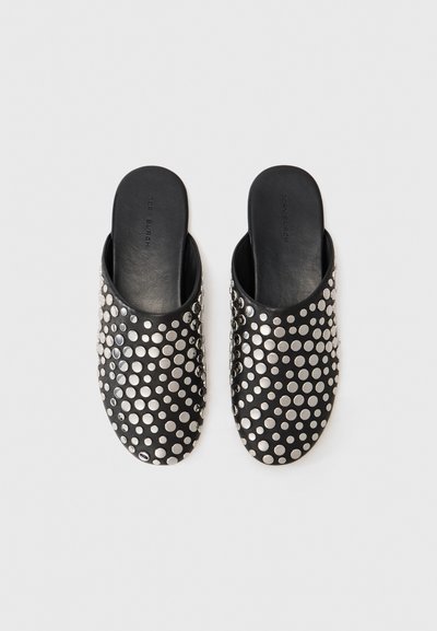 Sabots noirs en cuir à enfiler, ornés d'un motif texturé de clous en argent de tailles variées sur la surface supérieure.