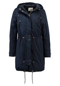 Parka aislante de color azul marino con cintura ajustable mediante cordón, cierre de cremallera y herrajes dorados. Cuenta con capucha y dos bolsillos laterales. Textura suave.