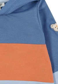 Sudadera con capucha en azul y coral con una textura suave. Presenta bloques de color horizontales y un parche de oso en el hombro.