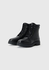 Botas de tobillo de cuero negro con un acabado liso, punta redonda y suela gruesa y texturizada. Presenta ojales y cordones en tono dorado para un ajuste seguro.