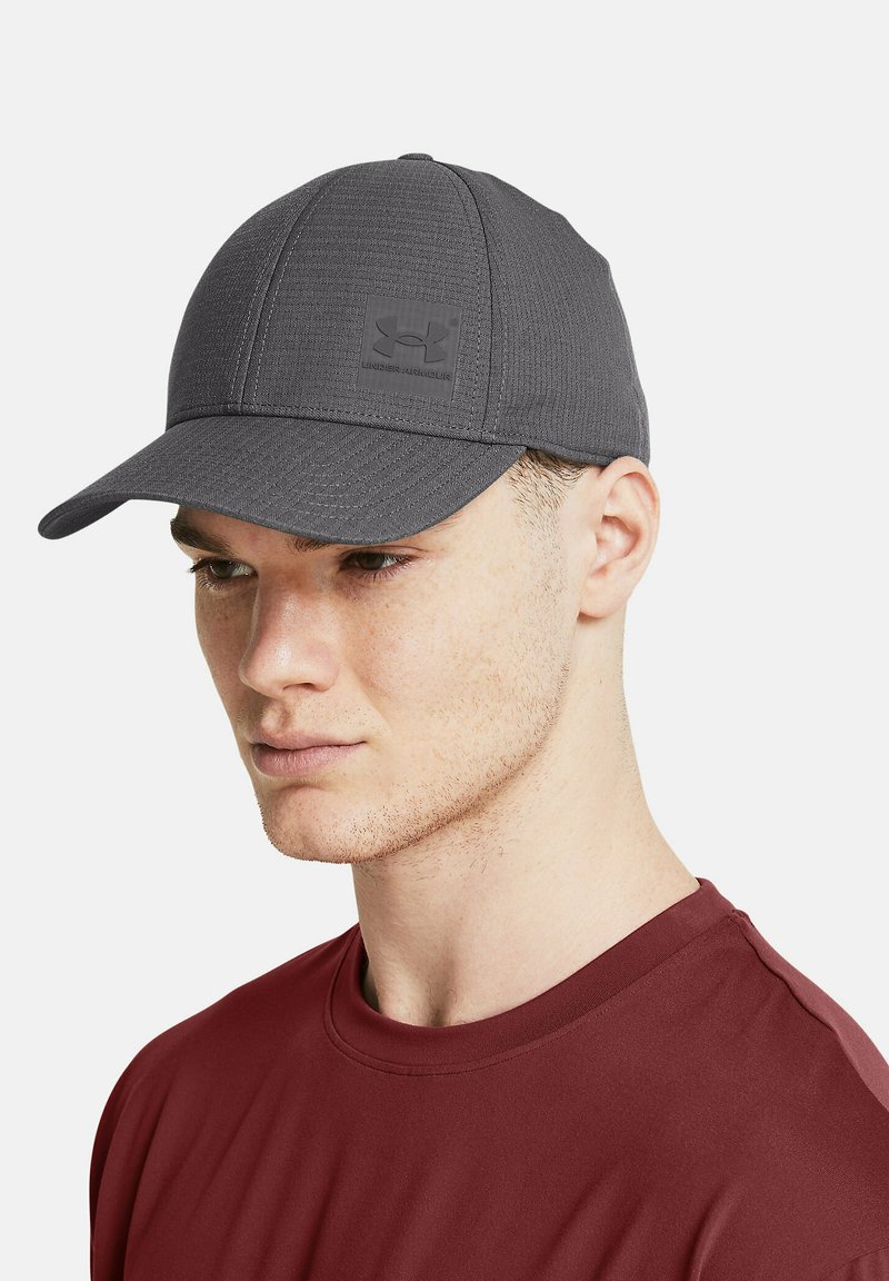 Grå baseballcap med en struktureret design, der har et tekstureret stof og et logo-patch på forsiden. Skærmen er let buet.