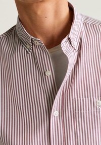 Overhemd met verticale rode en witte strepen, een puntkraag en een borstzak; gemaakt van geweven katoen.