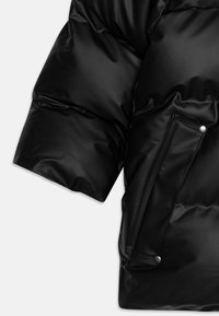 Manche de veste en duvet noire avec finition brillante, présentant un tissu texturé, une pochette latérale avec fermeture à bouton-pression.