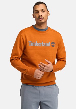 Felpa arancione con scollatura a girocollo, con il logo "Timberland" grigio. Polsini e orlo a costine, morbida texture, design casual.