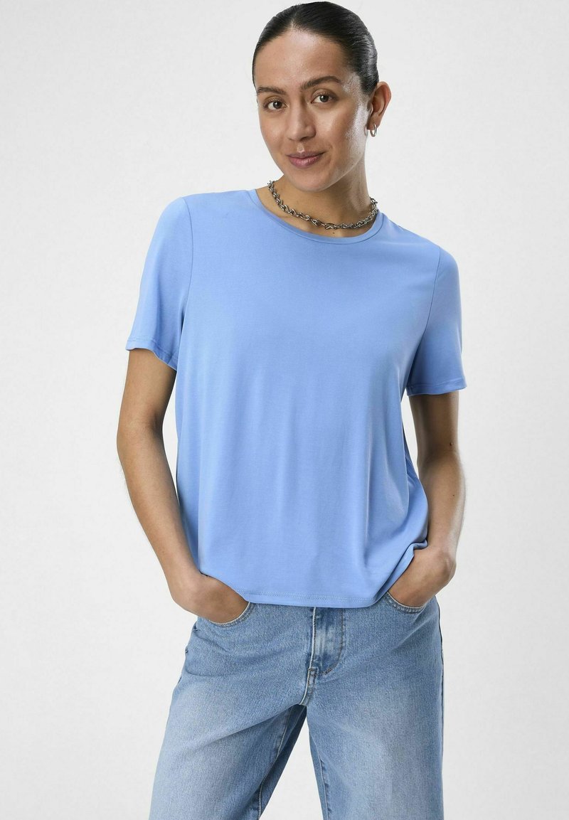Camiseta de manga corta azul claro en tejido suave con escote redondo. Combinada con un pantalón vaquero de corte holgado en un tono claro. Diseño sencillo sin acentos.
