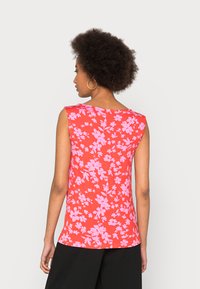 Top sem mangas, vermelho, com um padrão floral em tons de rosa. Textura suave e design ajustado, com um decote arredondado.