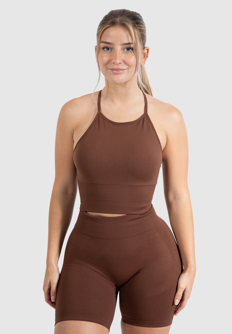 Bruine geribde sportset met een halternek crop top en high-waisted shorts met textuurpaneel details. Rekbare, nauwsluitende pasvorm.