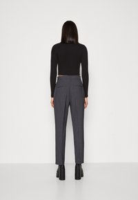 Grå skräddarsydda byxor med smal passform, utrustad med två bakfickor, i kombination med en svart kortärmad topp. Strukturerad tyg med subtilt mönster.