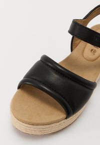 Sorte svart lærplattform sandaler med to brede stropper og en teksturert tan fotseng. Har en jute-innpakket såle og minimal sømdetalj.