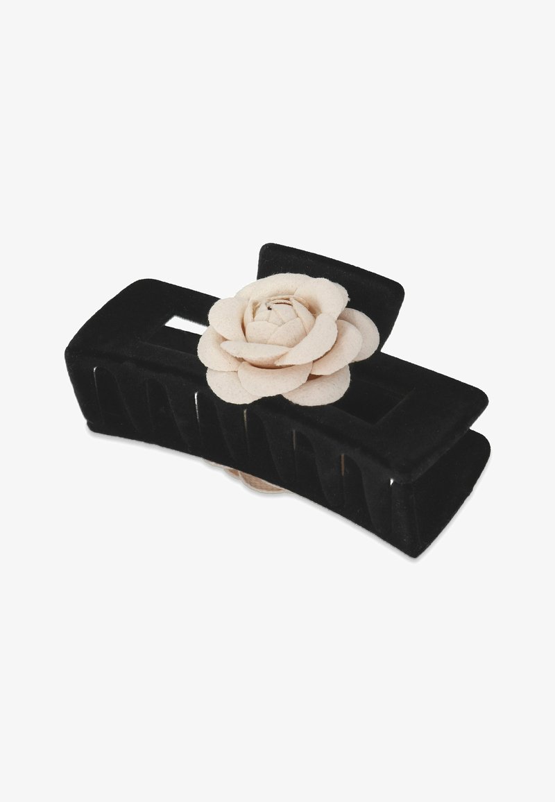 Zwarte fluwelen haarclutch met een lichtbeige vilten bloemenaccent, met een rechthoekige vorm en een geperforeerd ontwerp voor grip en stijl.