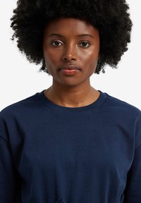 Marineblaues Sweatshirt mit Rundhalsausschnitt und gerippten Bündchen. Der Stoff wirkt glatt und leicht strukturiert. Keine Muster oder Akzente sichtbar.