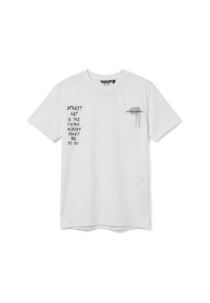 Maglietta bianca a maniche corte con testo nero "STREET ART IS THE THING NOBODY ASKED YOU TO DO" sul lato sinistro e piccolo logo con goccia di vernice sul lato destro.