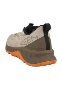 Beżowe buty sportowe z oddychającą siateczką, szarymi akcentami, pomarańczową, teksturowaną podeszwą oraz pętelką na pięcie ułatwiającą zakładanie.