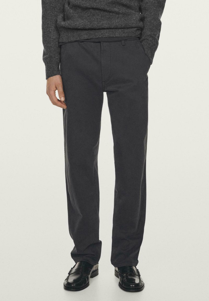 Ciemnoszare spodnie o prostych nogawkach, wykonane z mieszanki bawełny. Posiadają ukryte zapięcie z przodu oraz boczne kieszenie. Dopasowane do czarnych butów wizytowych.