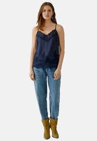 Navy satin camisole with lace trim and ombre effect, paired with light blue baggy jeans and tan suede boots. Simple design and soft texture.