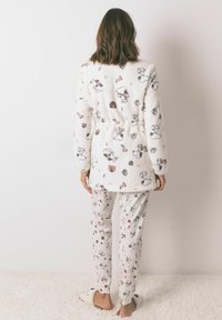 Białe, puszyste piżamy składające się z wzorzystego płaszcza i spodni z rysunkami z kreskówek. Płaszcz ma związany w pasie krój i długie rękawy.