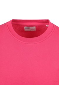 Heldroze katoen t-shirt met een ronde hals, met een zachte, gladde textuur en een minimalistisch ontwerp. Label zichtbaar aan de binnenkant van de kraag.
