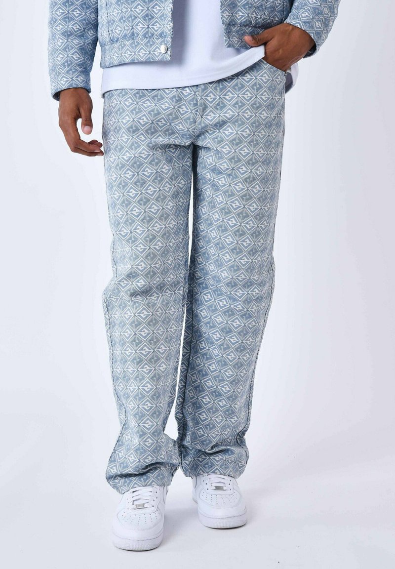 Blauwe broek met een geometrisch patroon, gemaakt van stof met een gladde textuur, gecombineerd met witte sneakers.