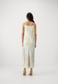 Lång, ärmlös klänning med en gradient av pastellfärger, som har ett mjukt, flödande tyg och en subtil batik-effekt.