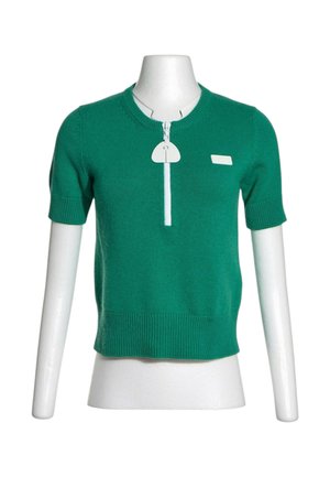 Groen gebreid topje met korte mouwen, geribde zoom en manchetten, witte rits aan de voorkant en kleine rechthoekige patch op de borst.