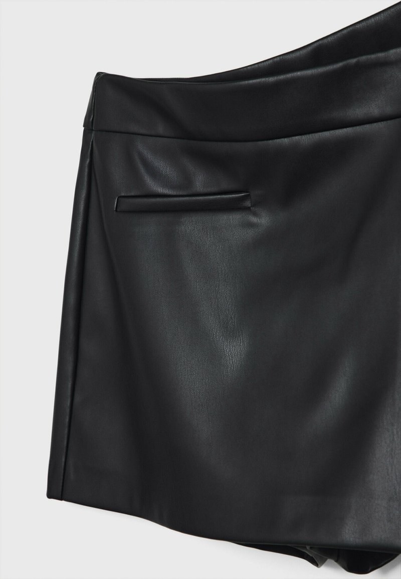 Gonna in pelle nera con una texture liscia, dotata di una tasca laterale discreta e di un design del girovita curvo.