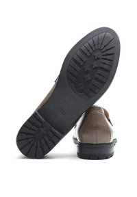 Braune Lederschuhe mit strukturierter Oberfläche, schwarzer Gummisohle mit Profilmuster und einem eingeprägten Logo auf der Sohle.