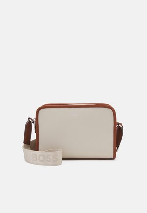 Suorakulmainen beige olkalaukku ruskeilla reunoilla, hopeisella vetoketjulla ja säädettävällä beigetävyisellä hihnalla, jossa on kohopainetut "BOSS"-kirjaimet.
